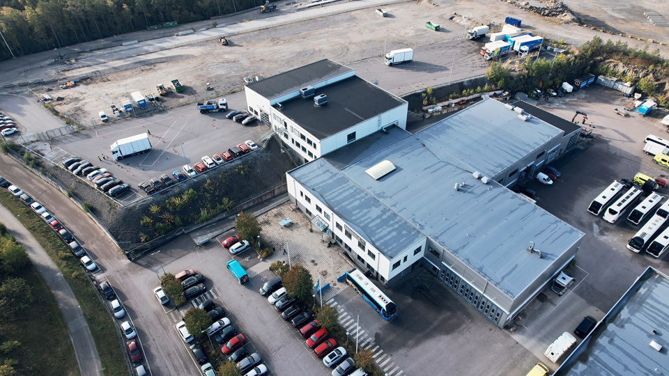 Drönarbild över skolan och skolans gård med bilar och andra fordon.