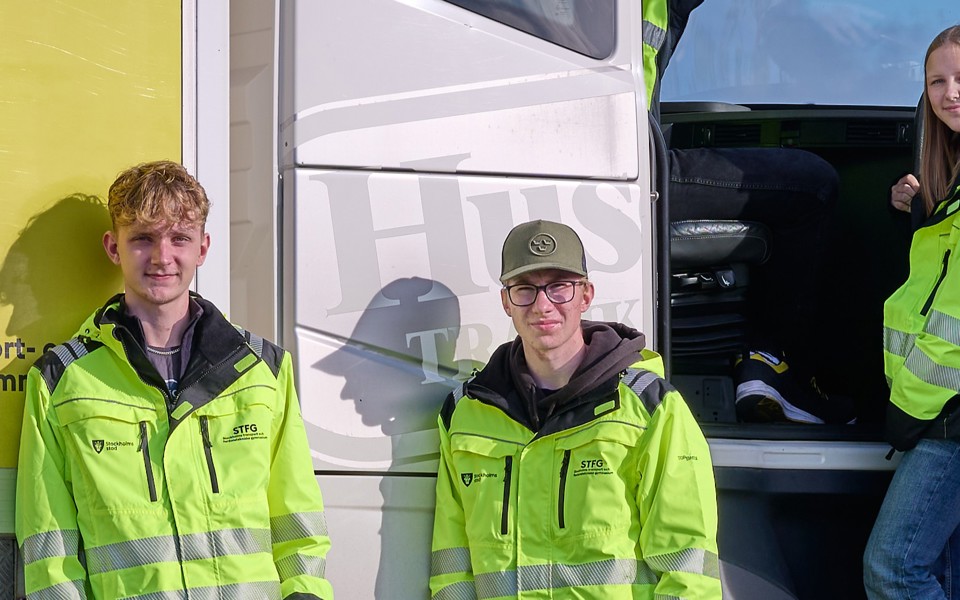 Tre elever står utanför en lastbilshytt.